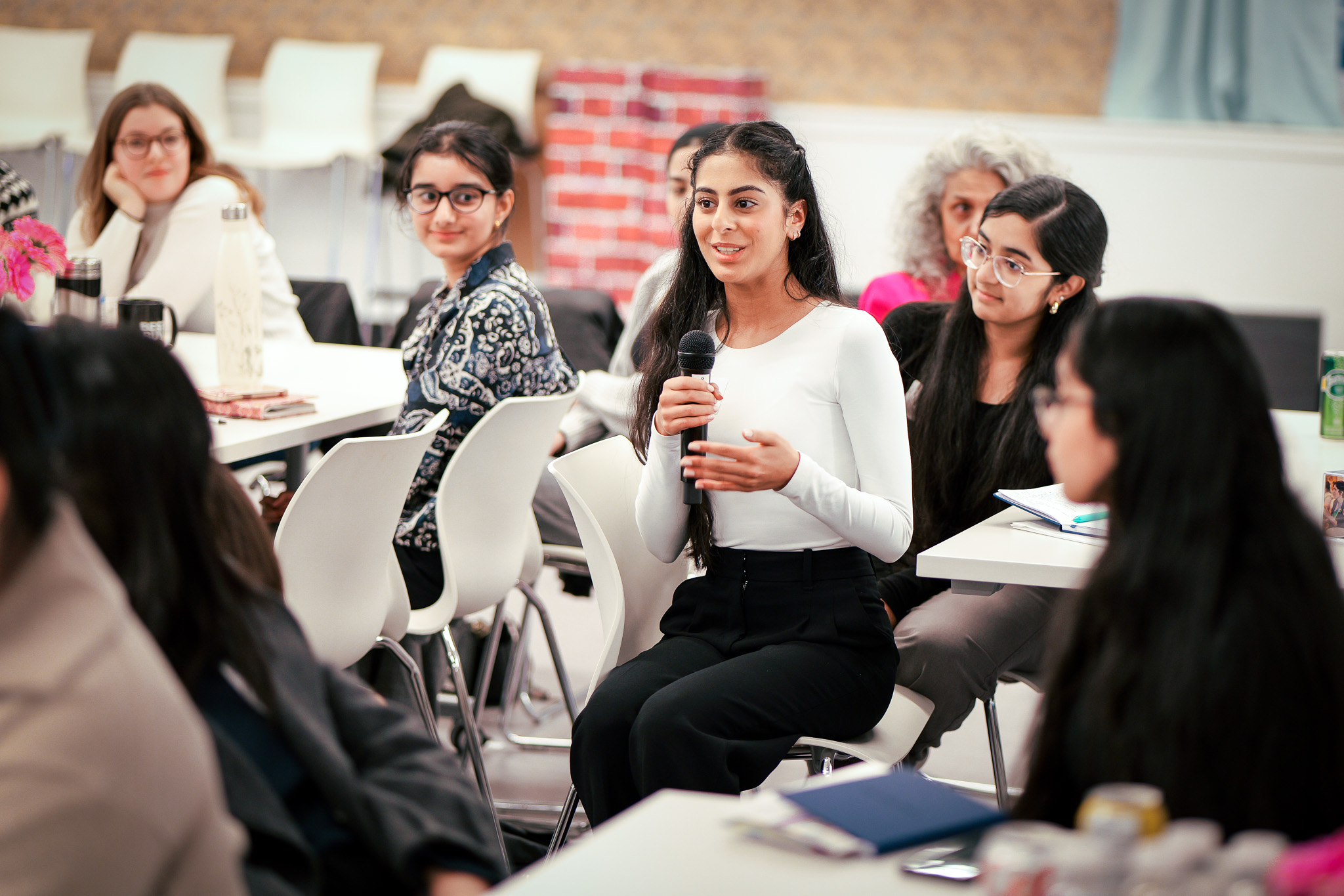 A young woman speaking in front of a group of peers